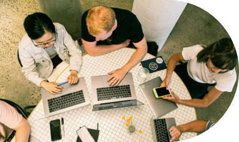 Brand Masters Marketing Agency Chicago - An Image of people in top view sitting down by a table with their laptops to represent our collaboration step in onboarding clients.